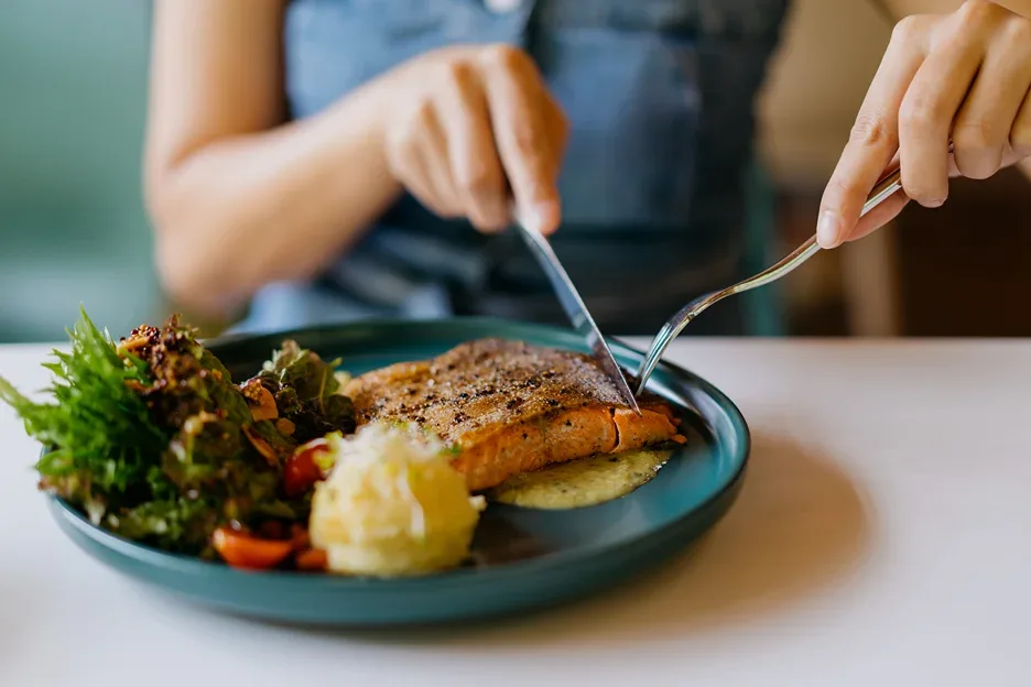 a woman eating fish and vegetable salad