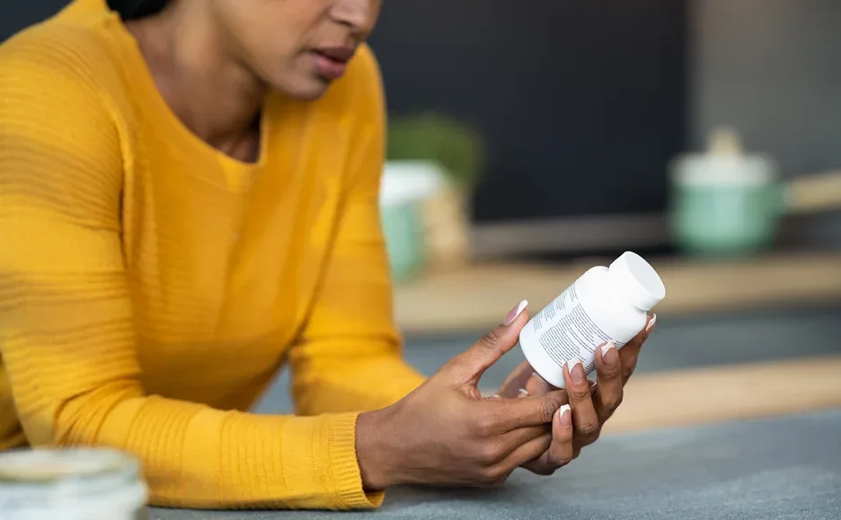 a woman checking the label of the pill bottle