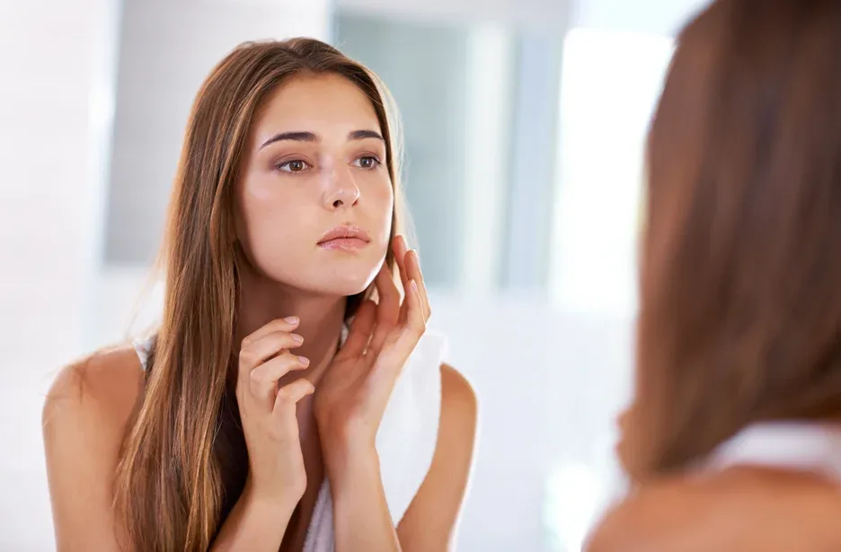 a woman checks out her face in front of the mirror
