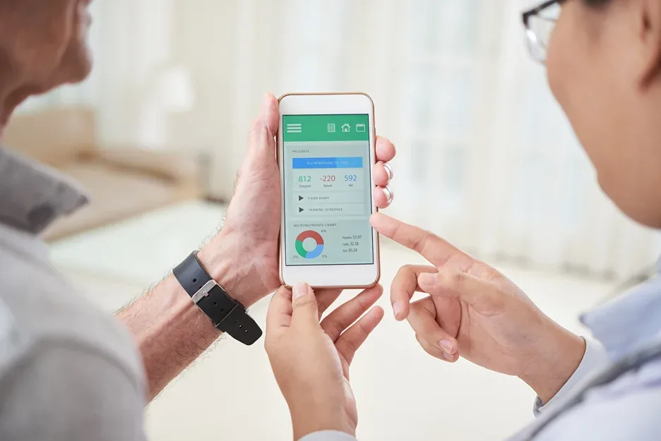 Two people looking at a smartphone app showing health metrics and a chart
