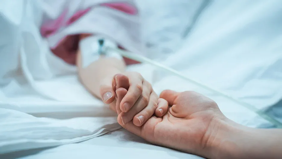 a sick child holds the mother's hand