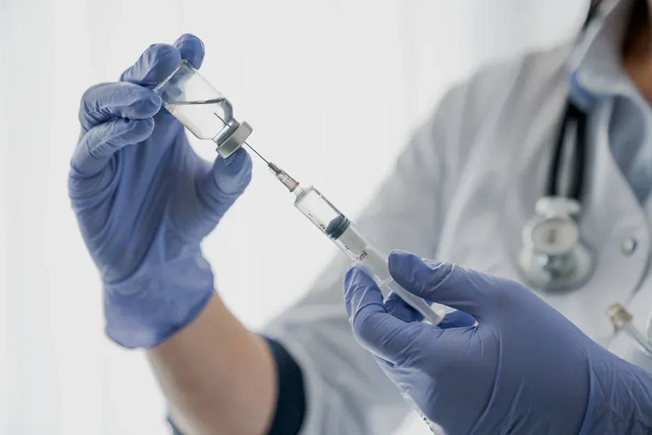 Medical provider holding a syringe and a vial of Covid vaccine