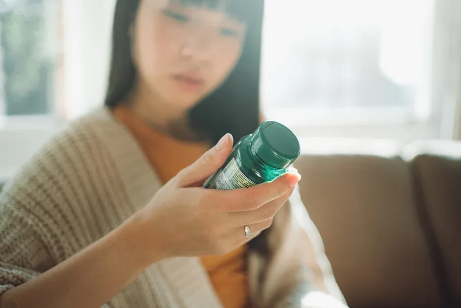 asian woman checking the label of the medicine bottle