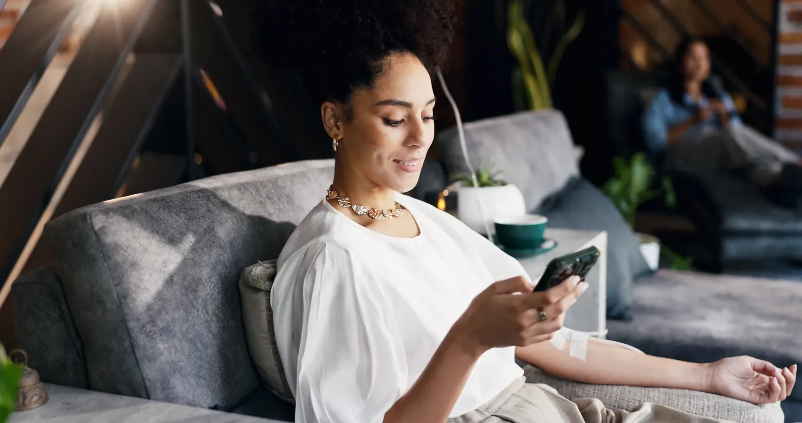 Smiling woman relaxing on a sofa in a lounge while looking at her phone