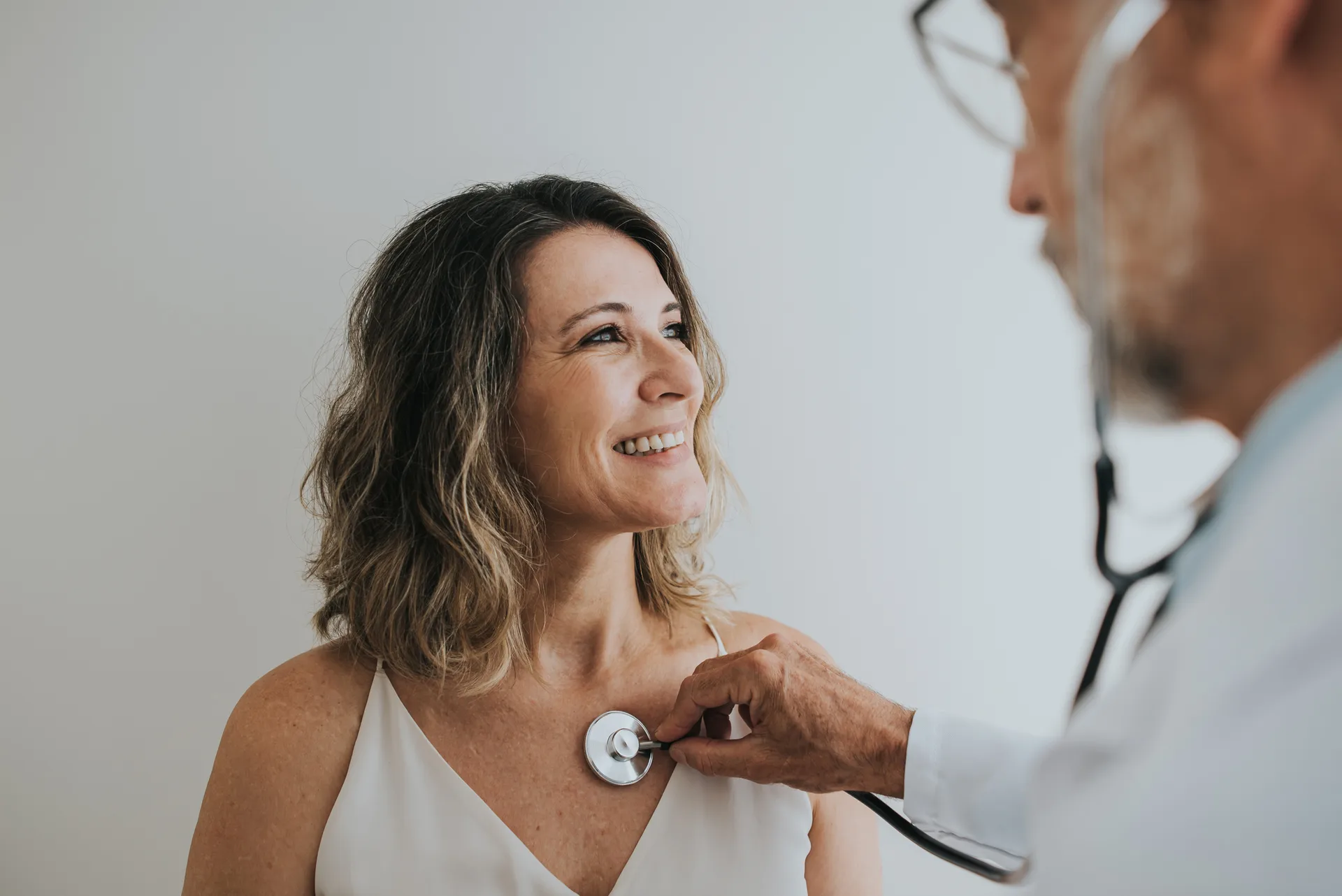 Smiling woman having her heart checked by a doctor with a stethoscope
