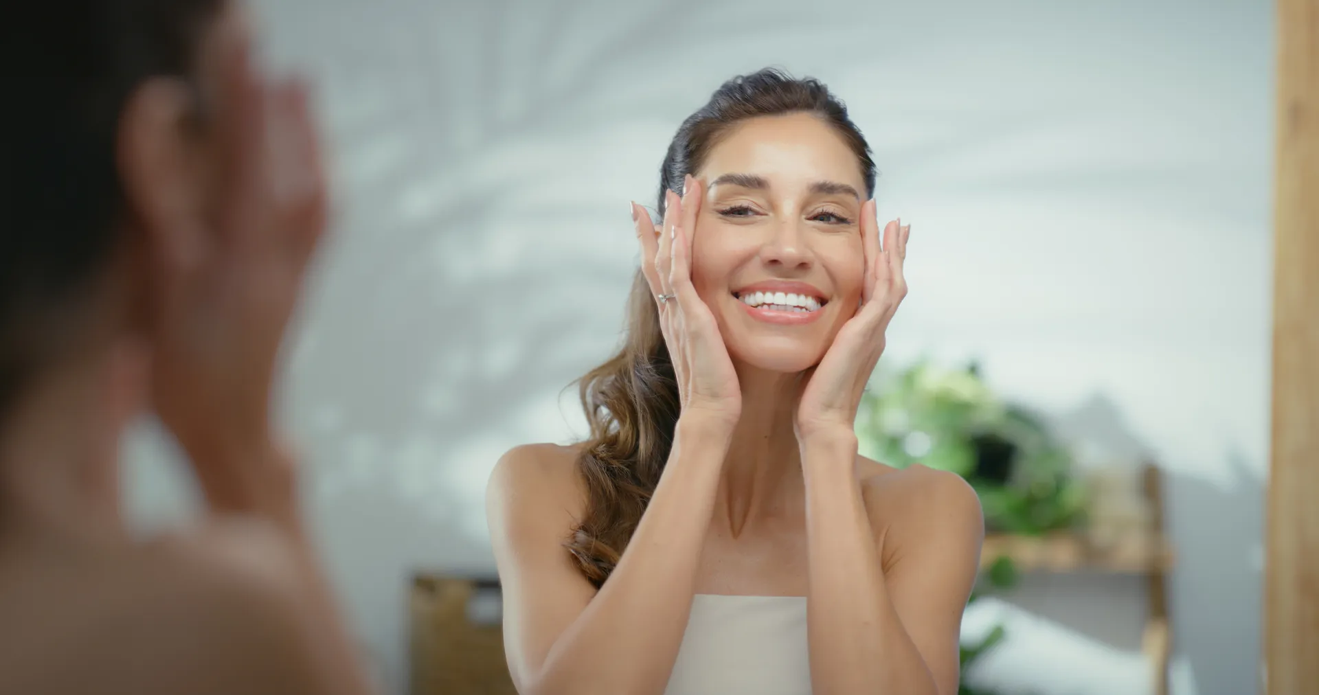 Smiling woman touching her face while looking in a mirror