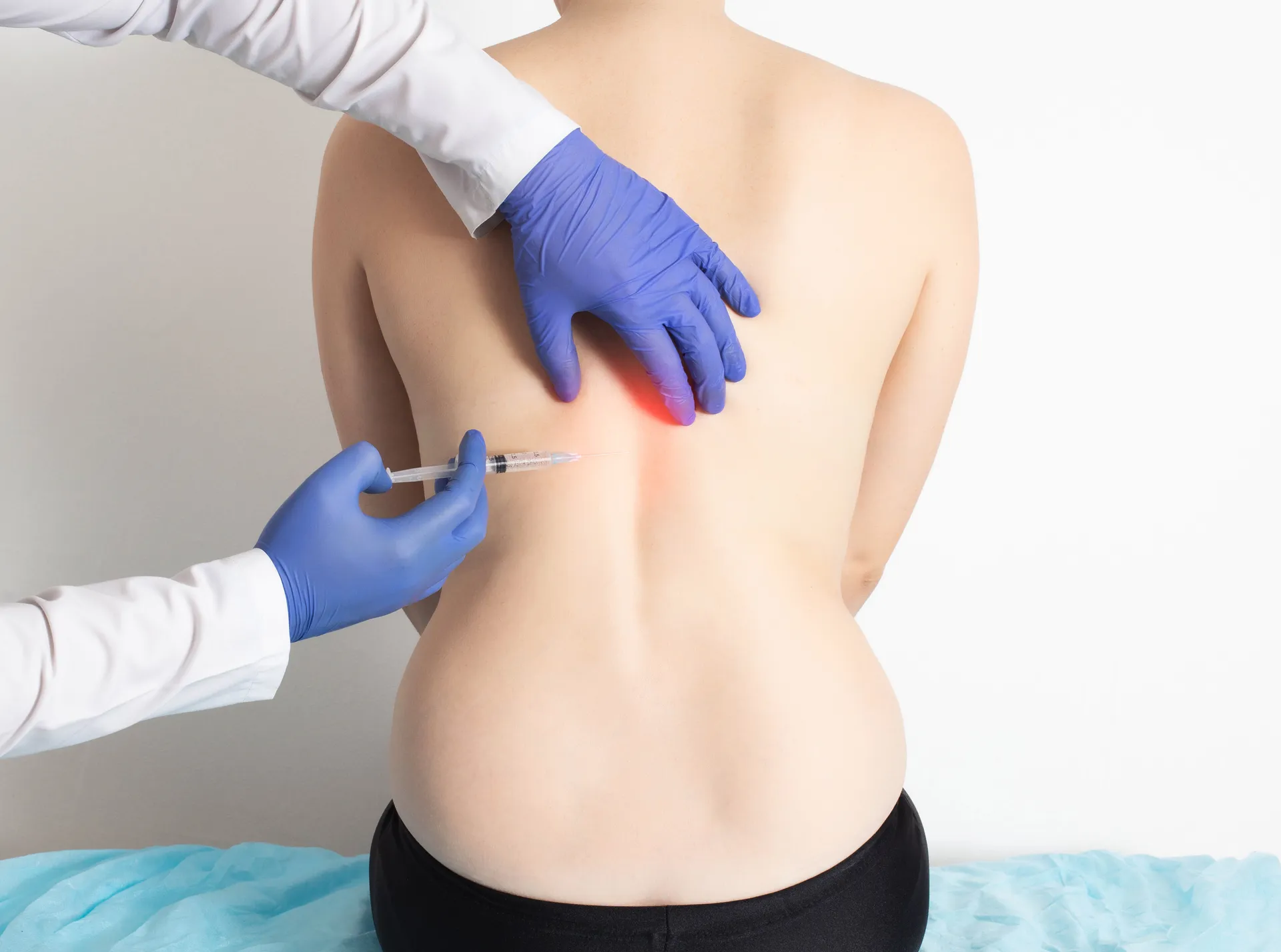 Gloved clinician giving an injection into a patient's upper back