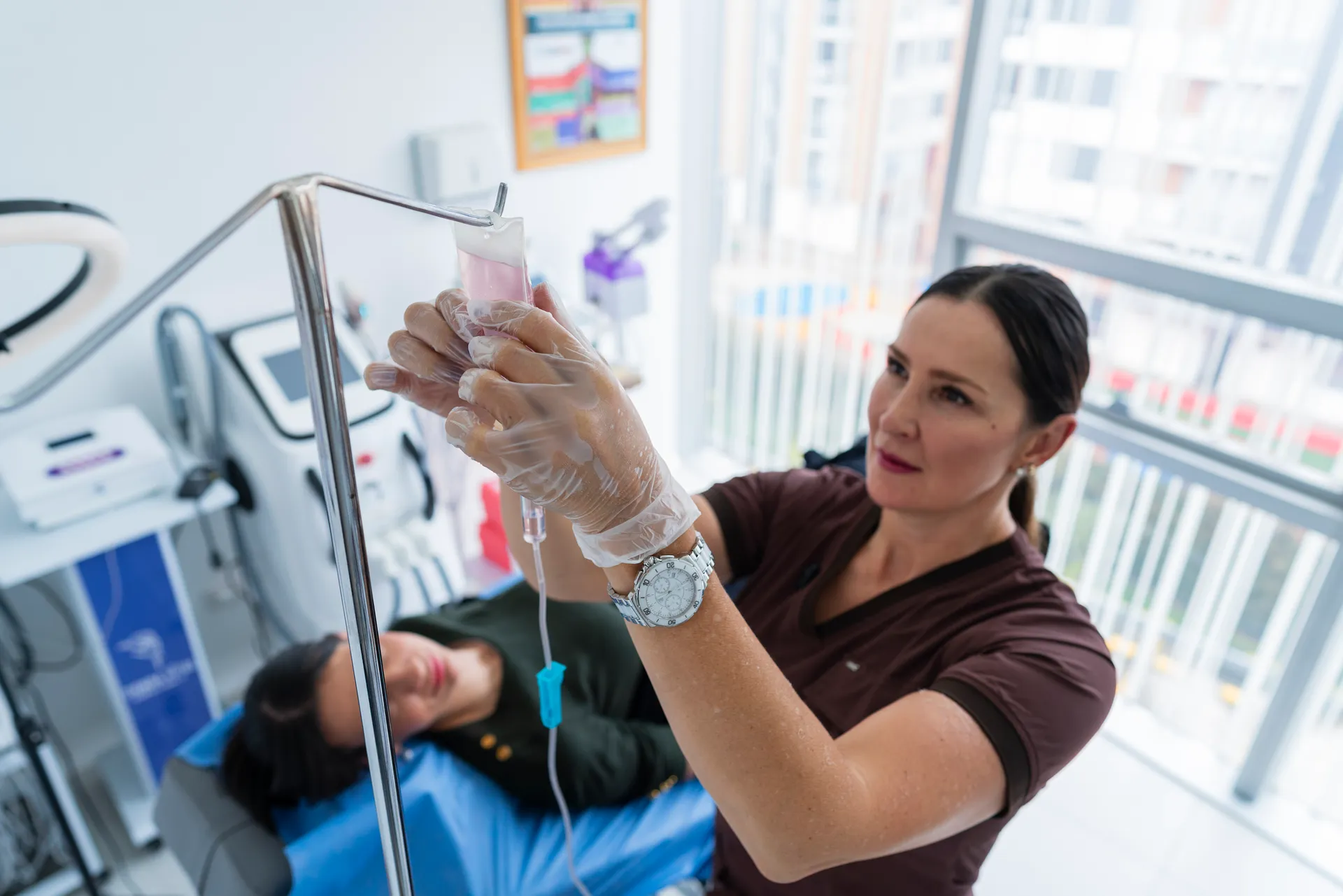 Clinician hangs an IV bag on a stand beside a patient reclining in a treatment chair
