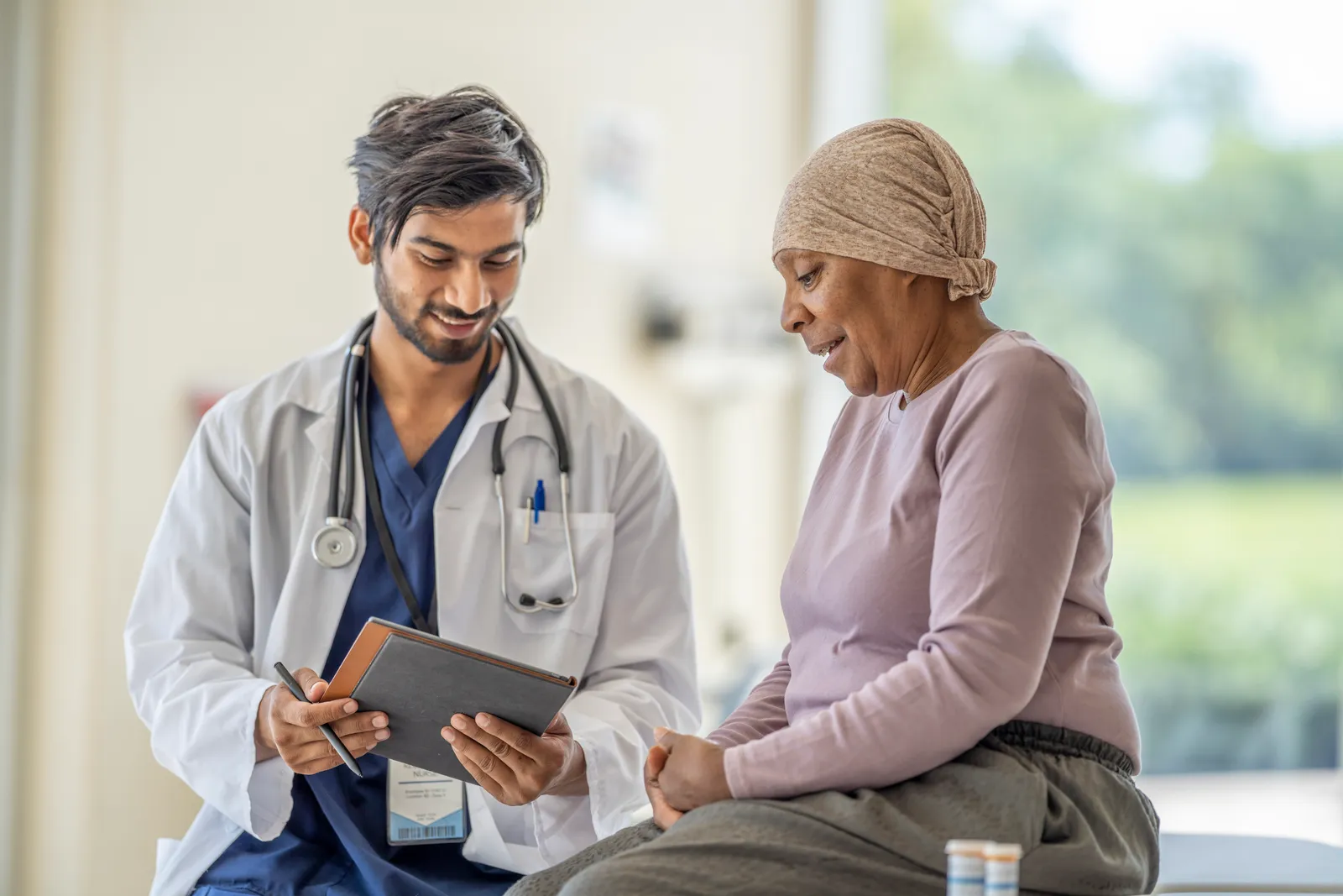 Doctor reviewing a tablet with a smiling older woman wearing a head wrap