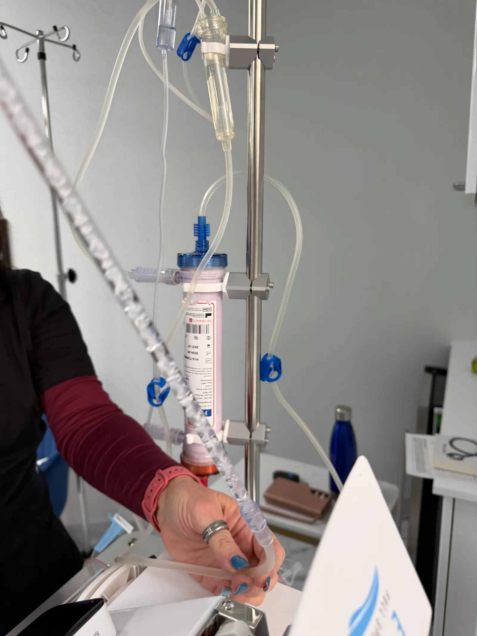 Clinician adjusting tubing on an IV pole with a filter canister during blood treatment