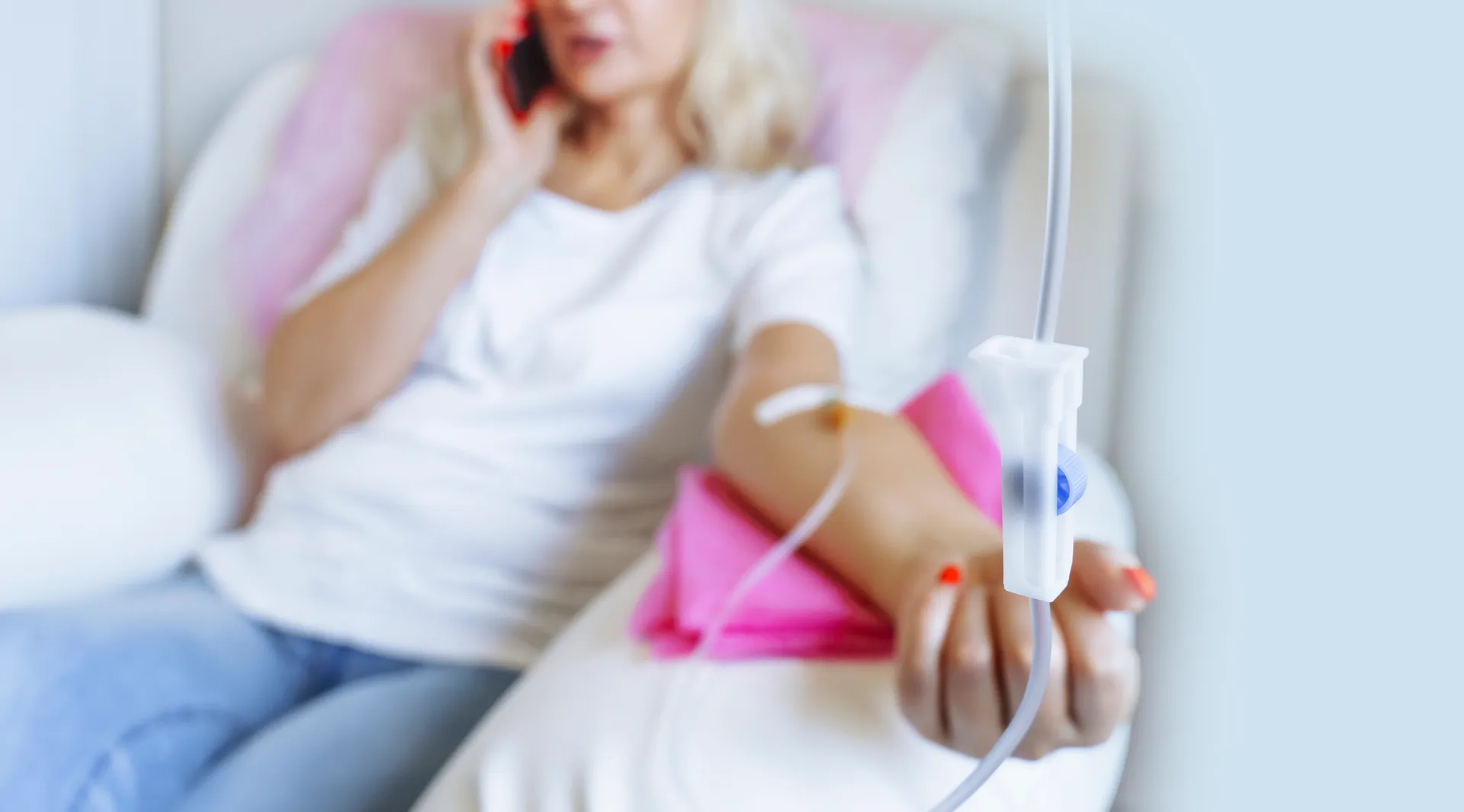 Woman talks on her phone while relaxing on a couch with an IV drip in her arm