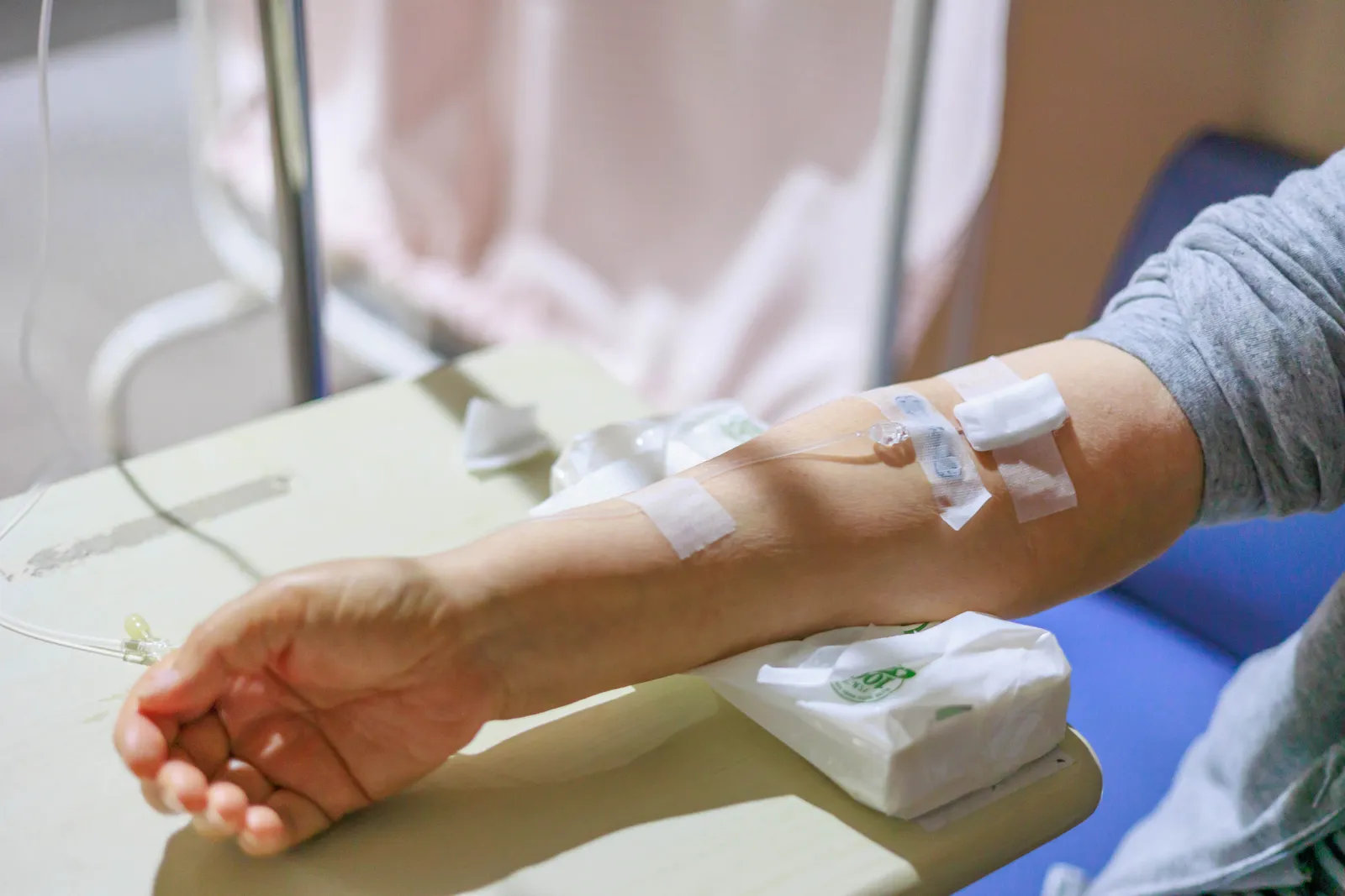 Patient's arm resting on a table with an IV line taped in place