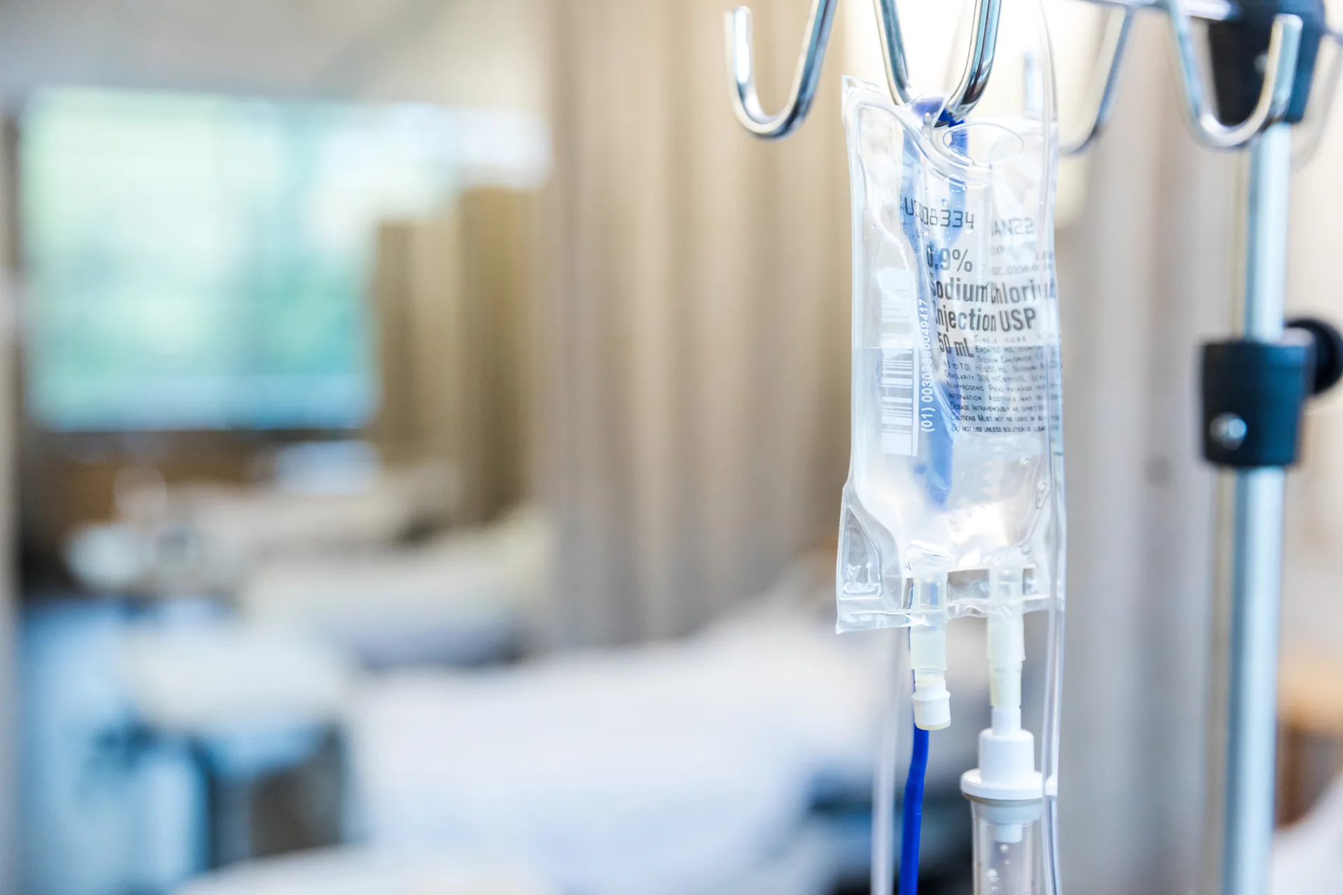 IV saline bag hanging on a pole in a clinical treatment room