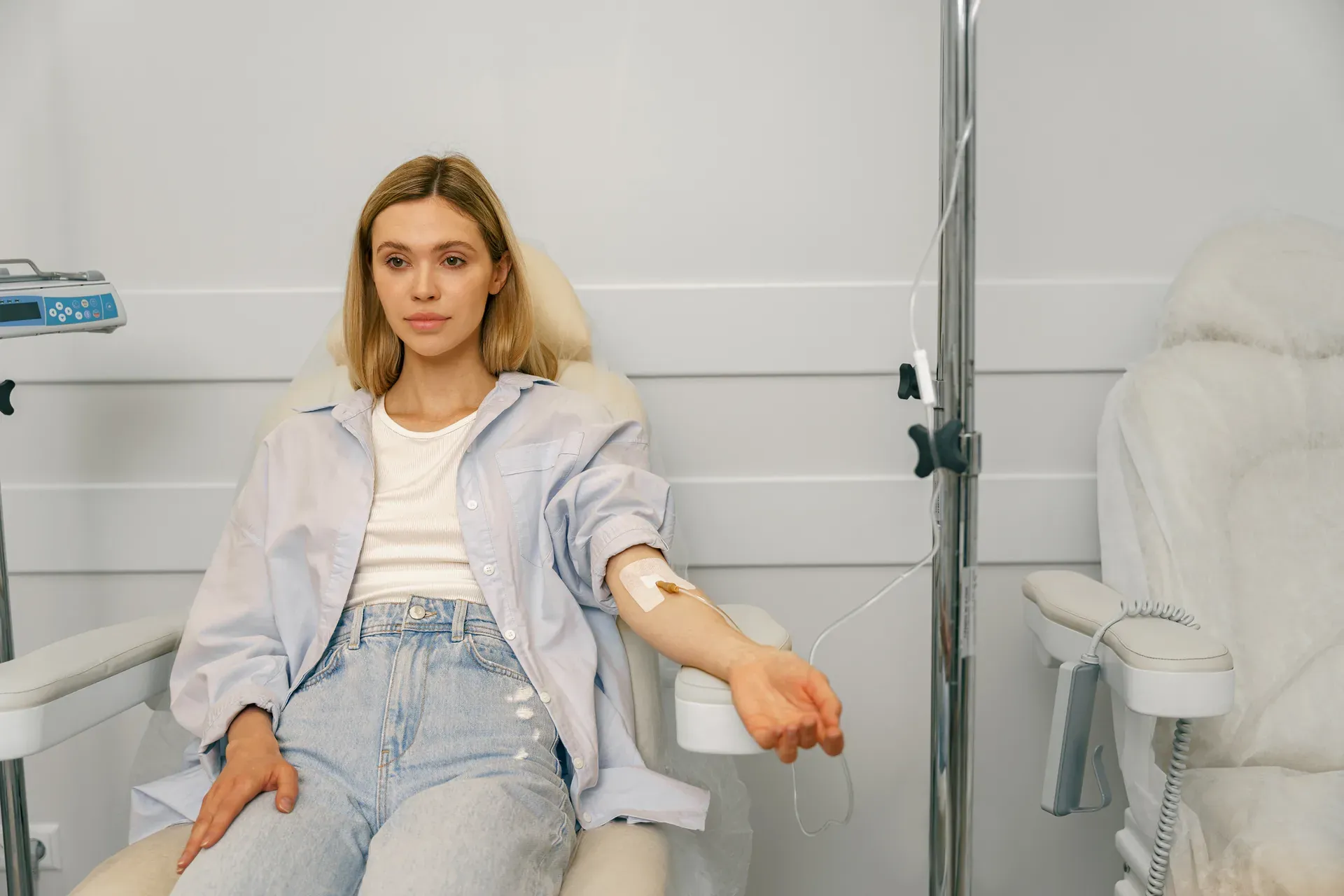 Young woman seated in a treatment chair receiving an IV infusion in her arm