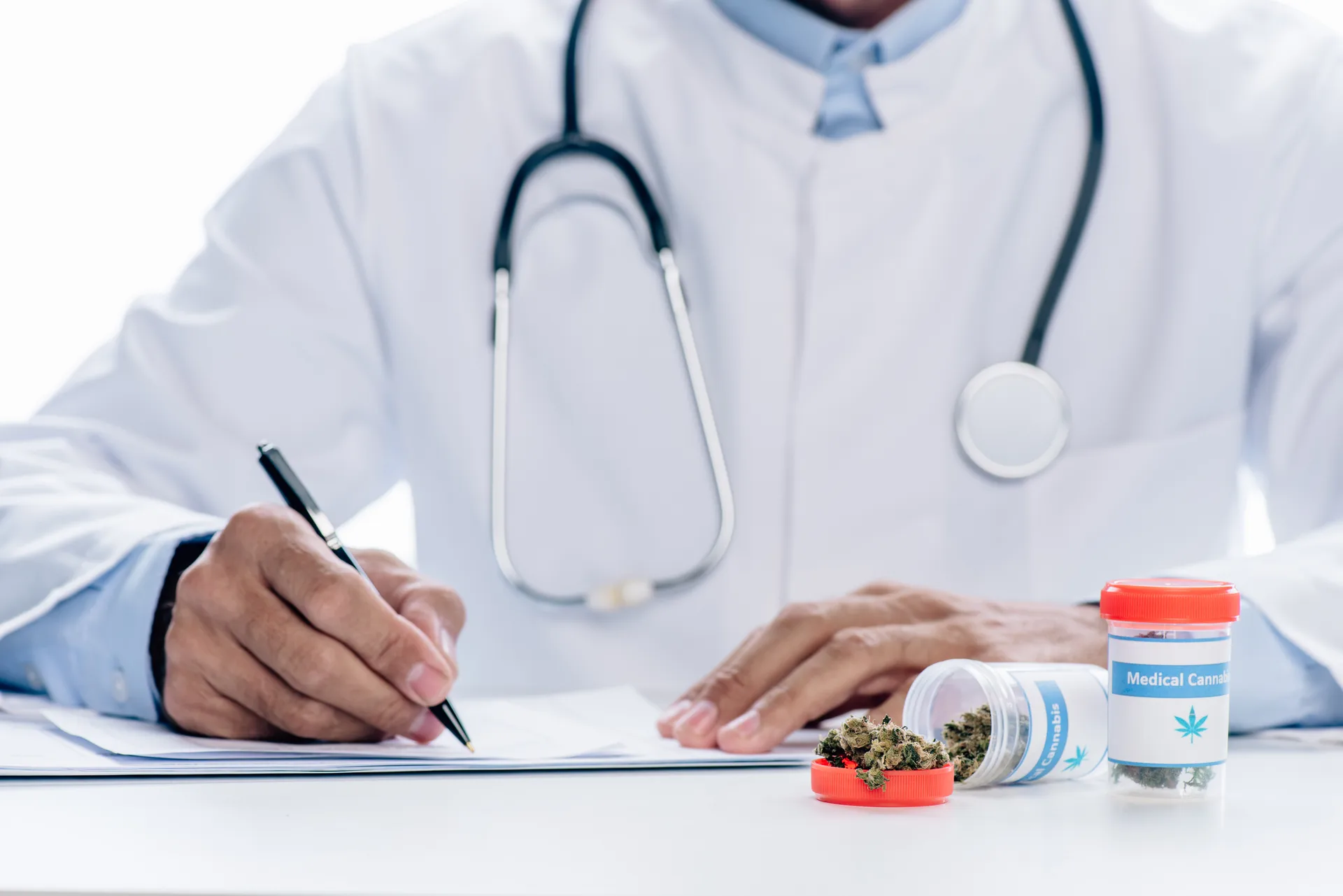 Doctor writing notes beside containers of dried cannabis labeled medical cannabis