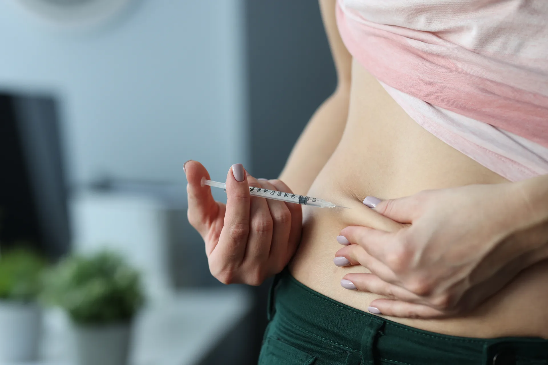 Woman pinching skin on her abdomen to give herself a syringe injection