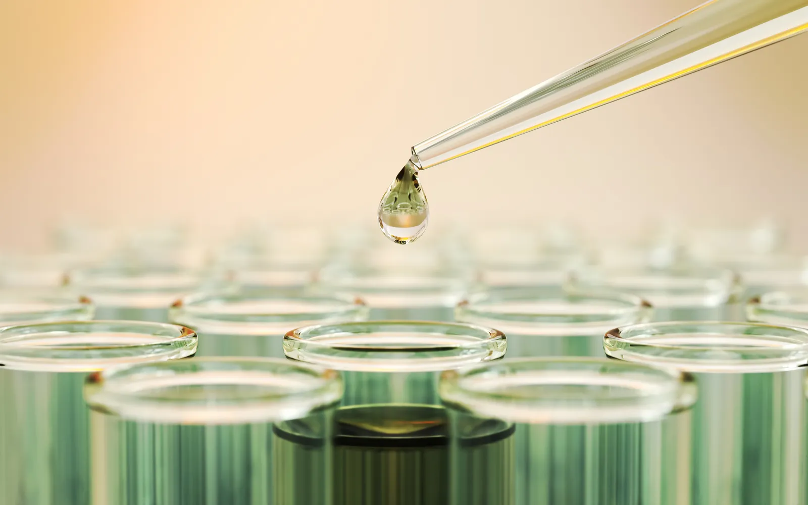 Dropper releasing a drop of liquid over rows of glass test tubes