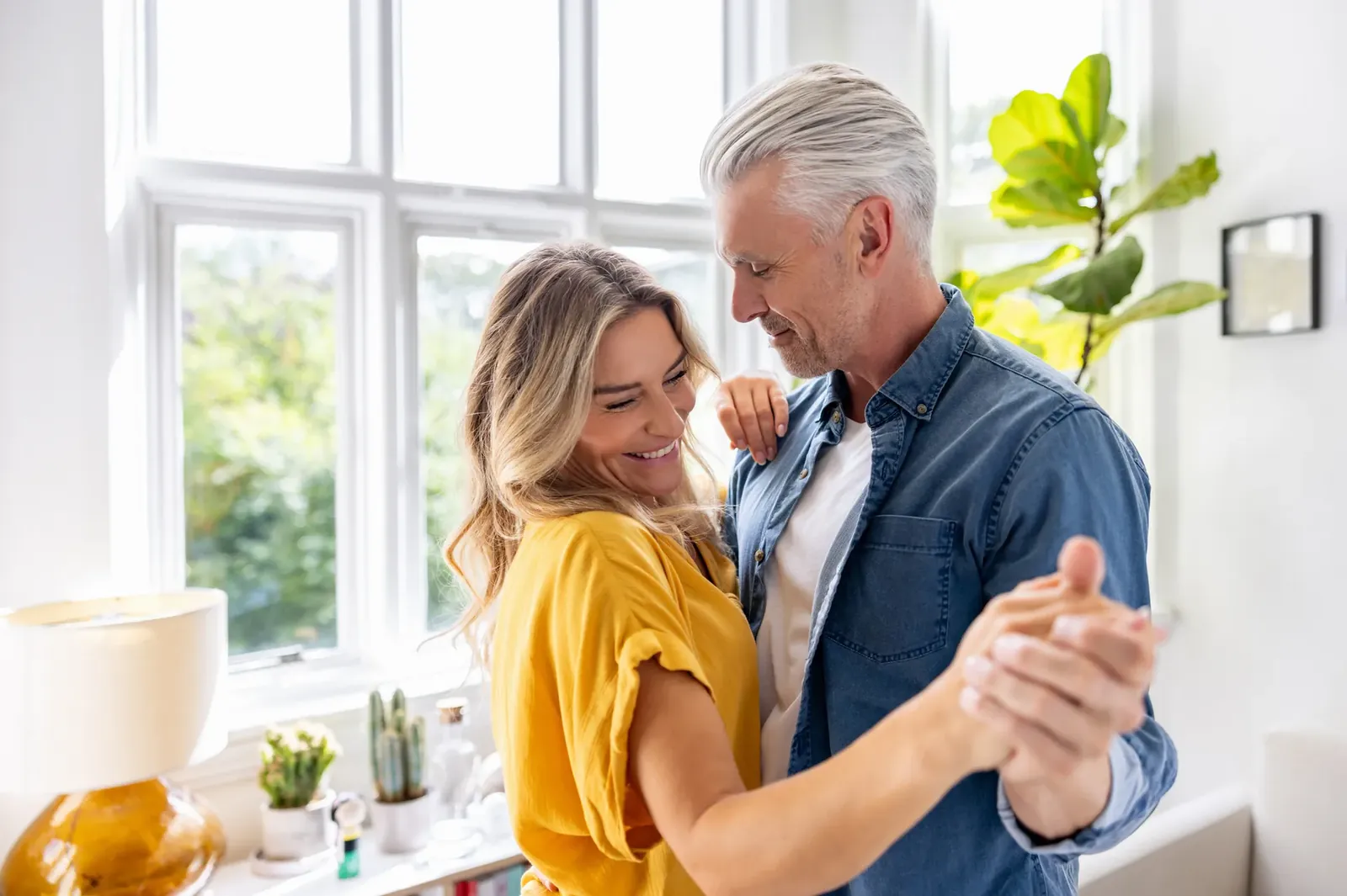 Smiling middle-aged couple dancing together in a bright living room