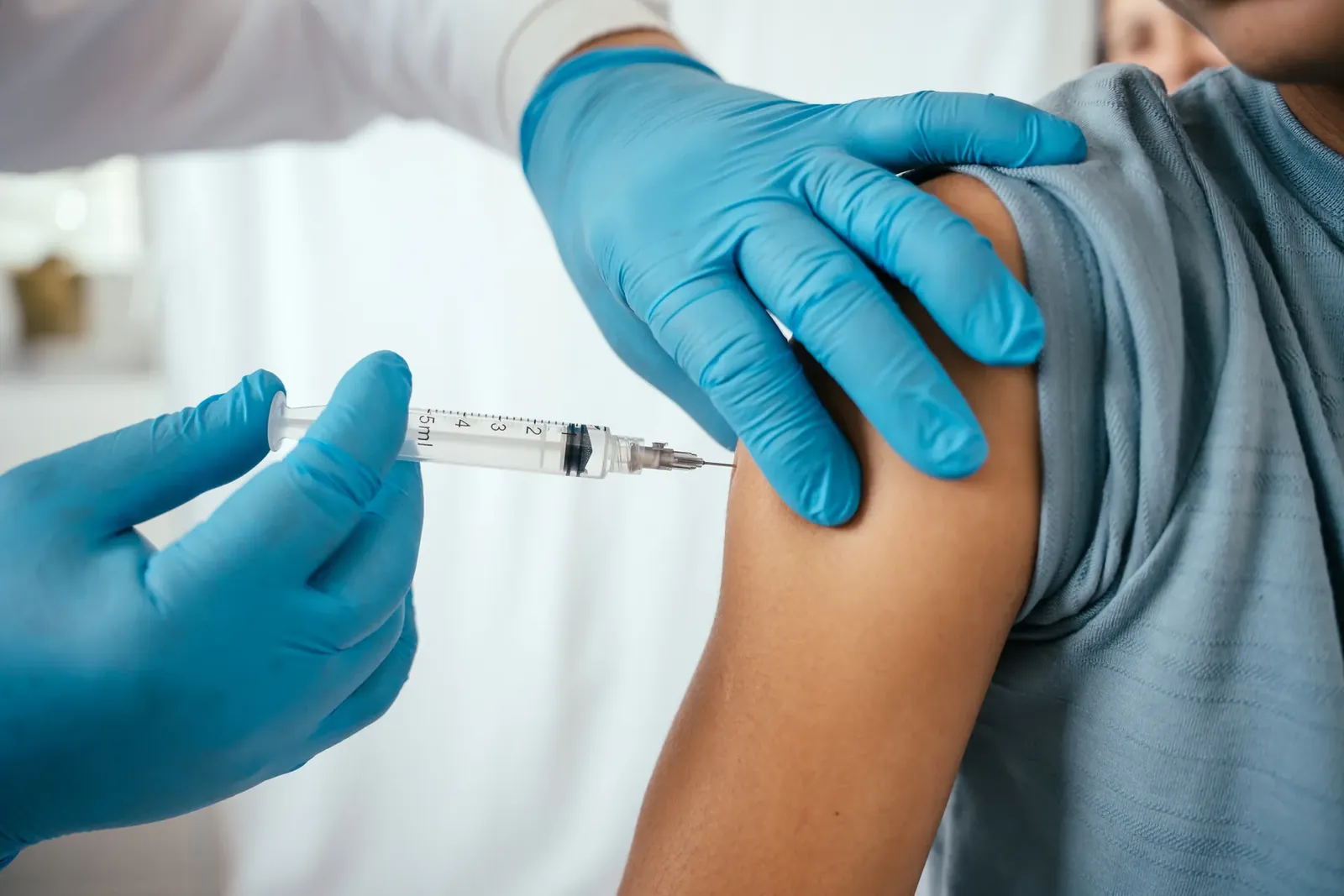 Gloved clinician giving an injection in a patient's upper arm