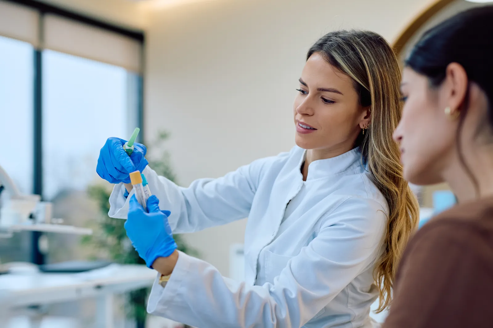 Clinician in a lab coat shows a sample tube to a patient