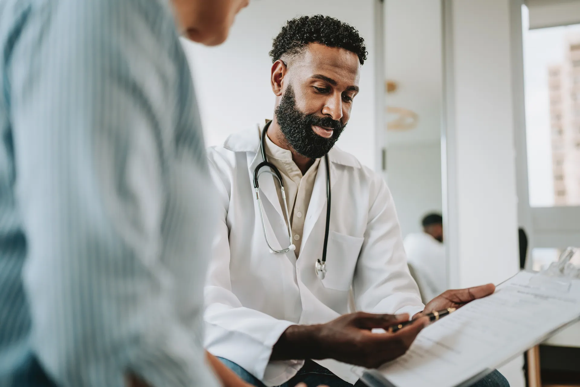 Doctor in a white coat reviewing a document on a clipboard with a patient