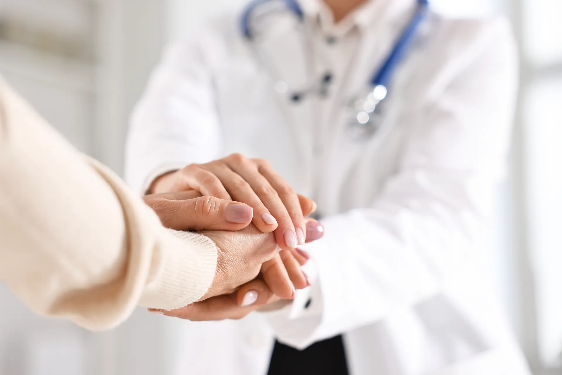 Doctor holding a patient's hands in both of hers in a gesture of support